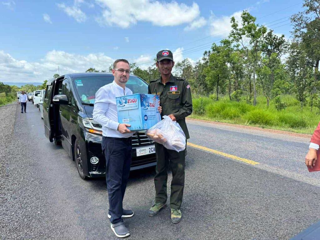 Stephan übergibt einem Soldaten Lebensmittelspenden und Wasser.