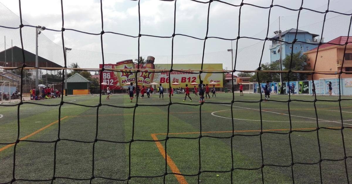 Zwei Schulmannschaften spielen auf einem Kunstrasenplatz Fußball.