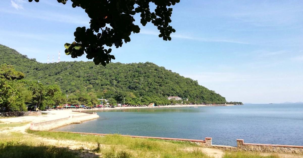 Blick auf Bucht mit Strand und bewaldete Hügel.